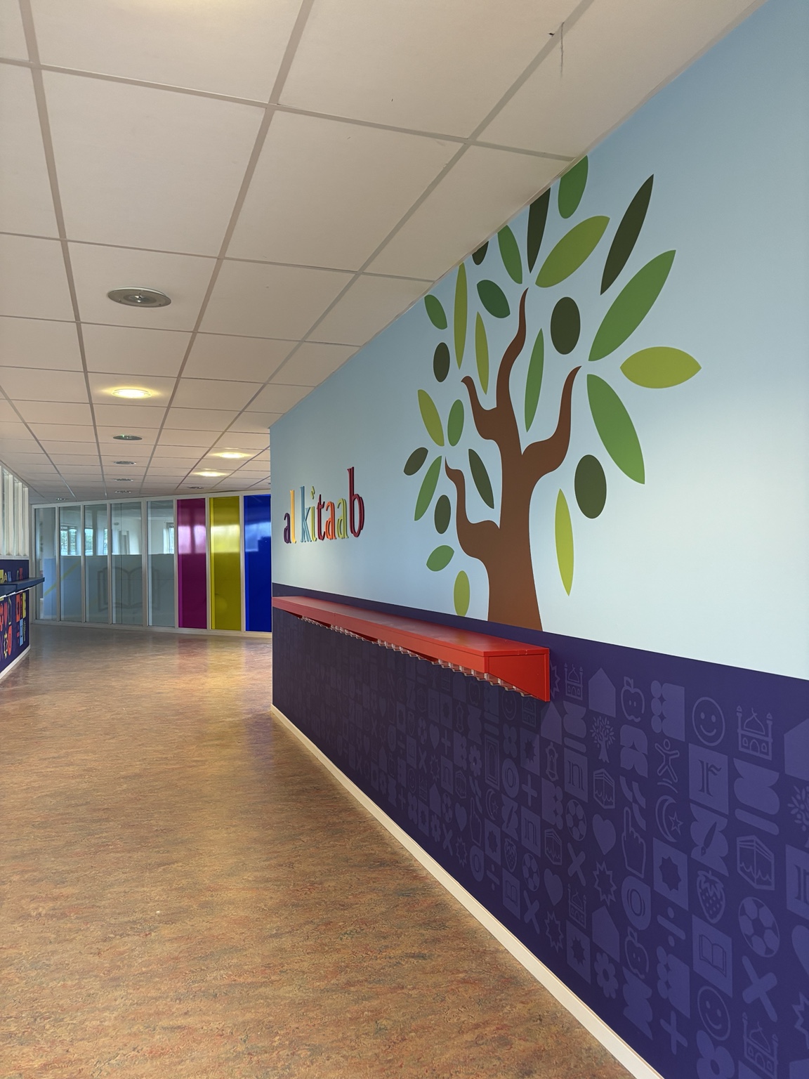 Gerestylede gang van basisschool Al Kitaab met wandbekleding, PET-viltlogo en gekleurde glasfolie