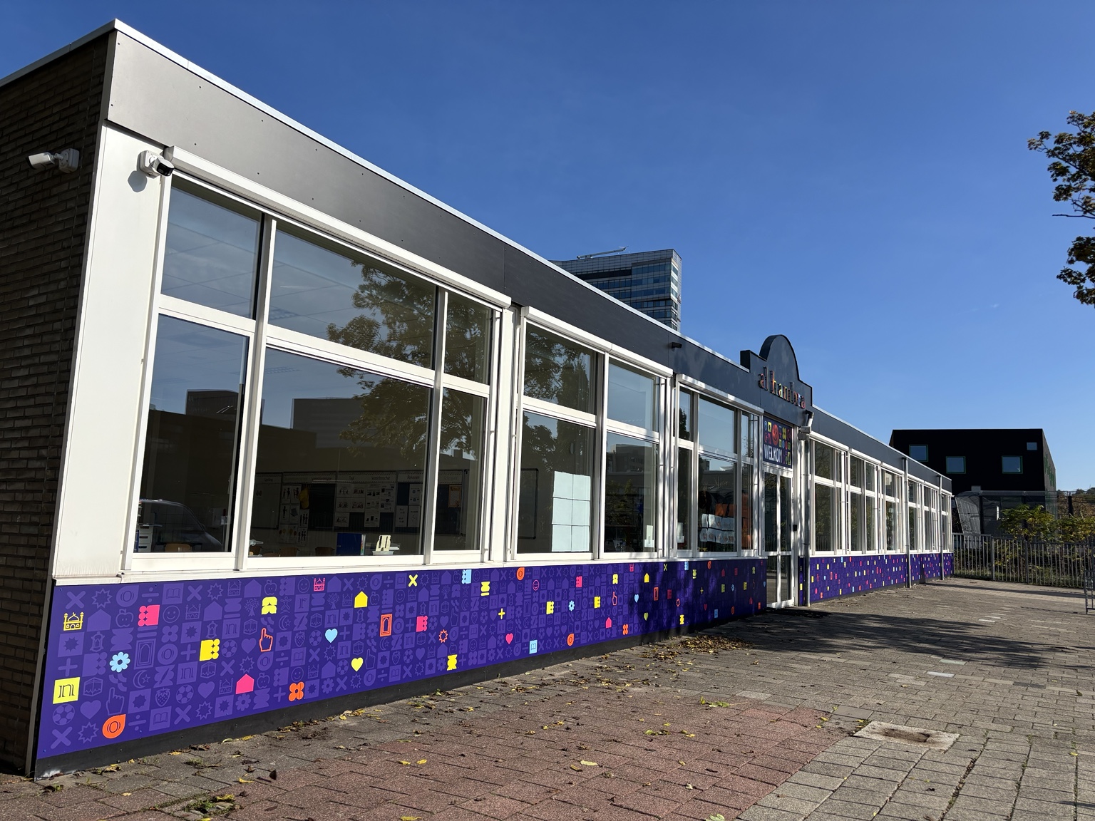 Lange gevel van basisschool Al Hambra met paarse bedrukte gevelpanelen