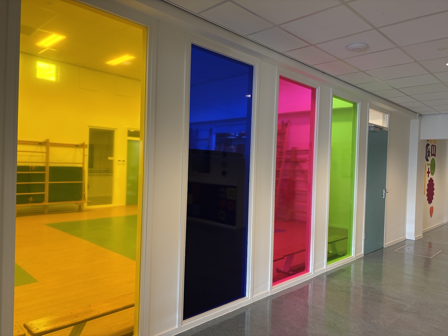 Gang met vier hoge ramen in transparant geel, blauw, roze en groen